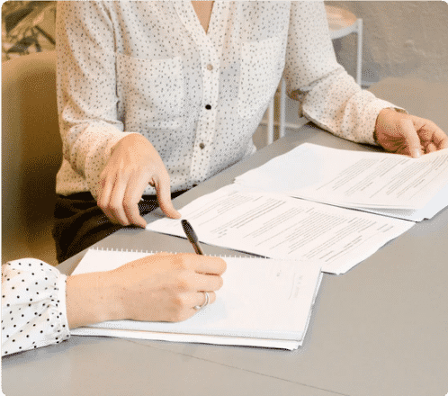 a woman signing a set of estate planning documents with the guidance of her lawyer