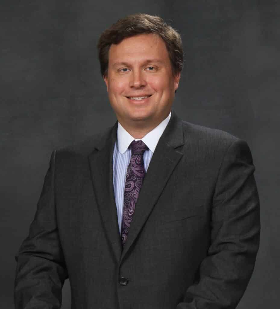 photo of Ryan Reiffert, San Antonio corporate transactional attorney wearing a dark suit and purple tie